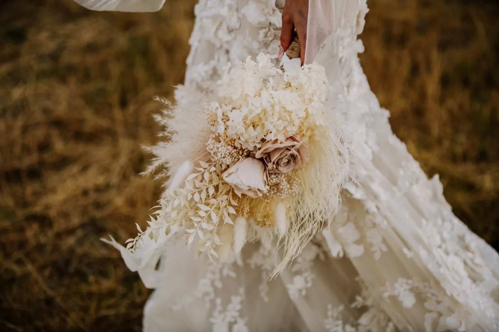 A dried-flower bridal bouquet against the dress