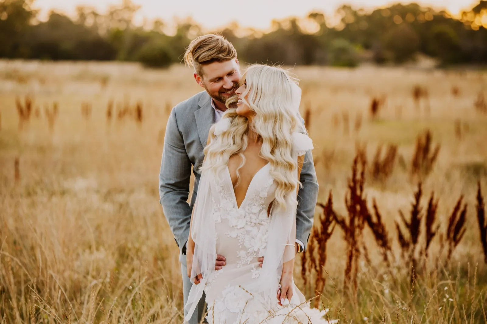 A couple laughing together in long golden grass