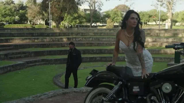 Wedding film still: bride beside a vintage motorcycle before the ceremony