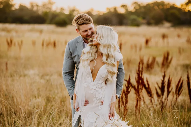 Bride and groom together in the golden field at sunset