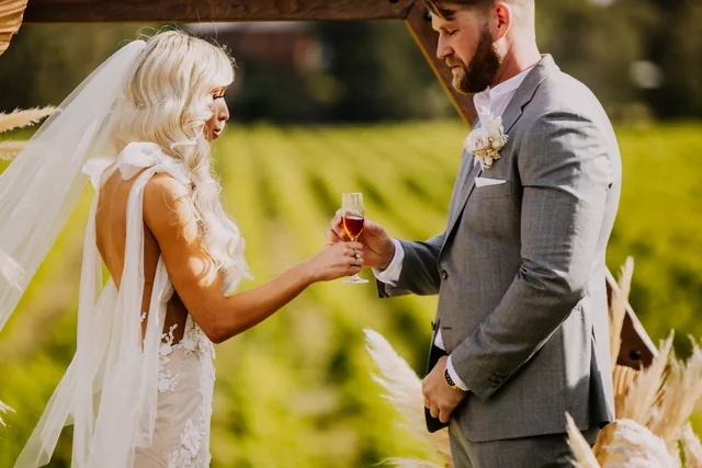 Bride handing her groom a drink among the Swan Valley vines