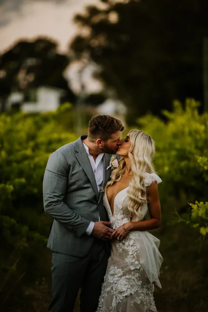 Bride and groom kissing among the vines