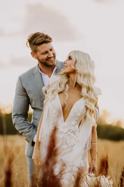 Groom holding his bride from behind in the long grass