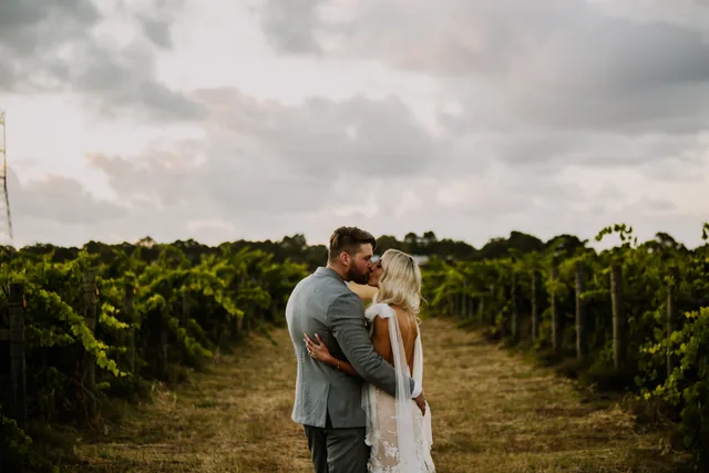 Couple kissing in a Swan Valley vine row at dusk