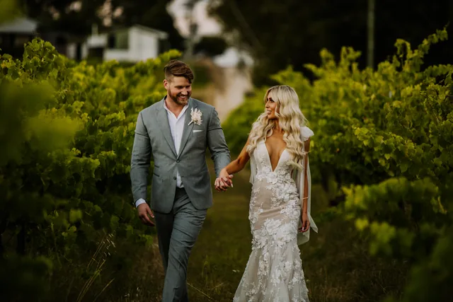 Couple walking hand in hand through the vines