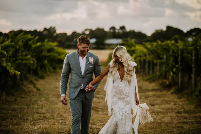 Couple walking hand in hand down a vine row