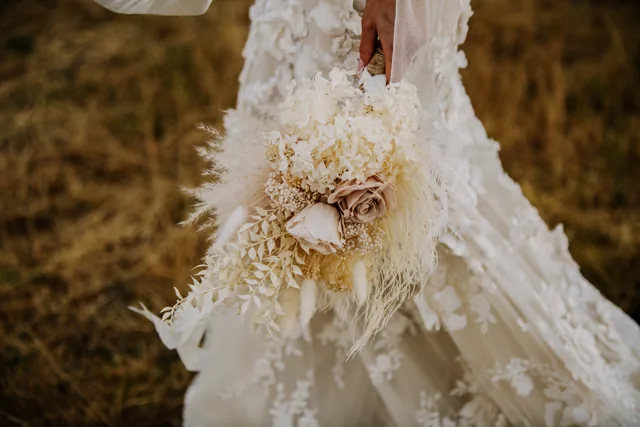 Detail of the bride's dried floral bouquet against her gown