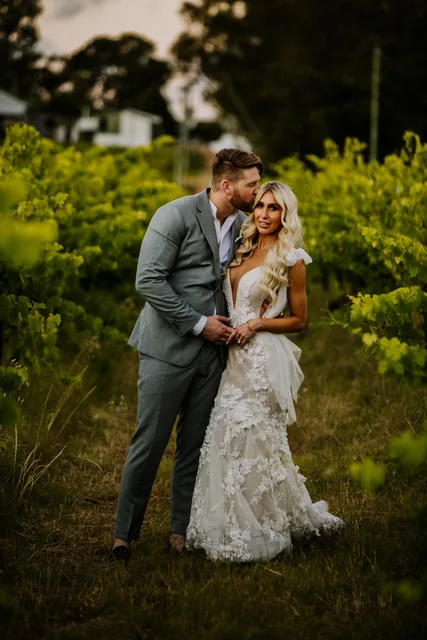 Bride and groom standing close together among the vines