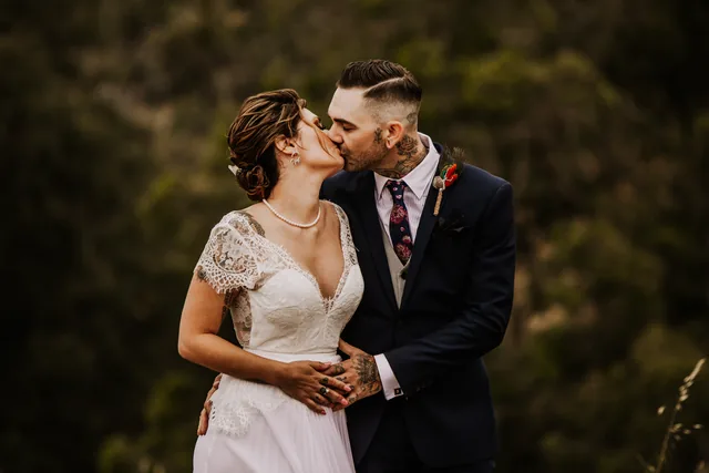 Bride and groom kissing in the long grass on the ridge