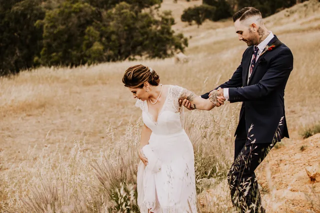 Groom leading his bride by the hand across the hillside