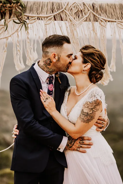 Couple kissing beneath the macrame ceremony arch