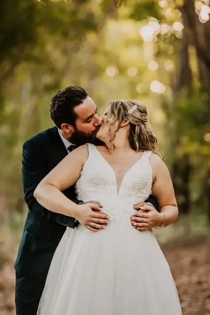 Groom kissing his bride's cheek in the afternoon light