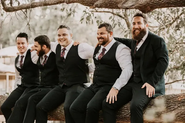 Groomsmen sitting along a tree branch