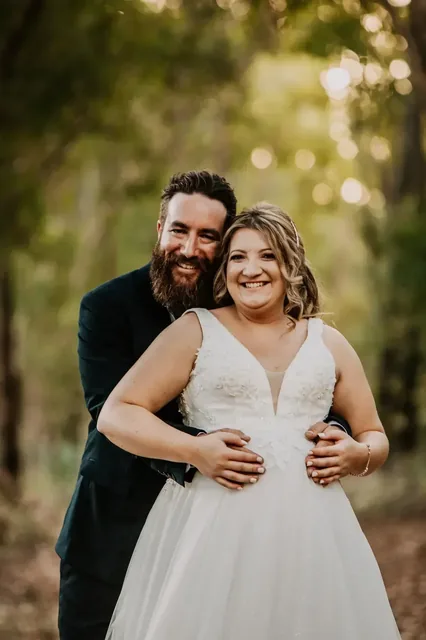 Bride and groom laughing together among the trees