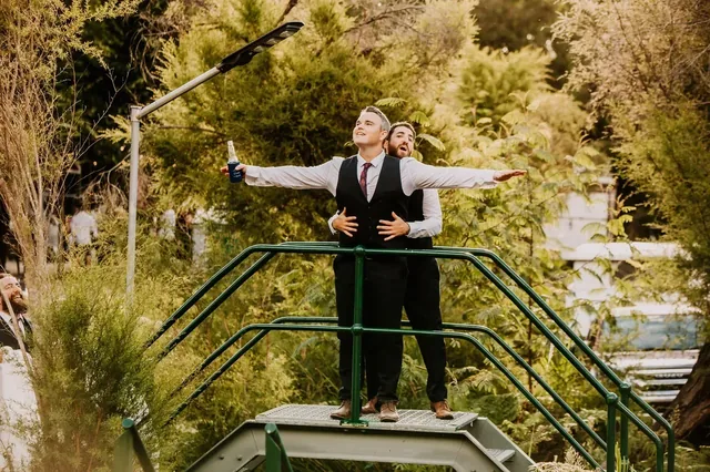 Groom standing with arms outstretched on the green bridge