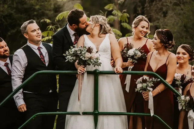 Bridal party on the bridge as the couple kiss