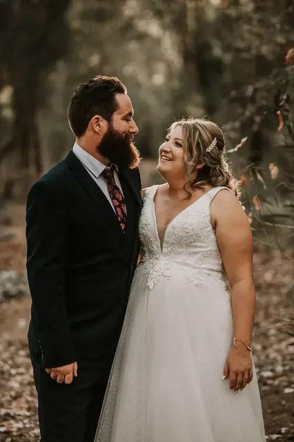Bride and groom smiling at each other in the bush