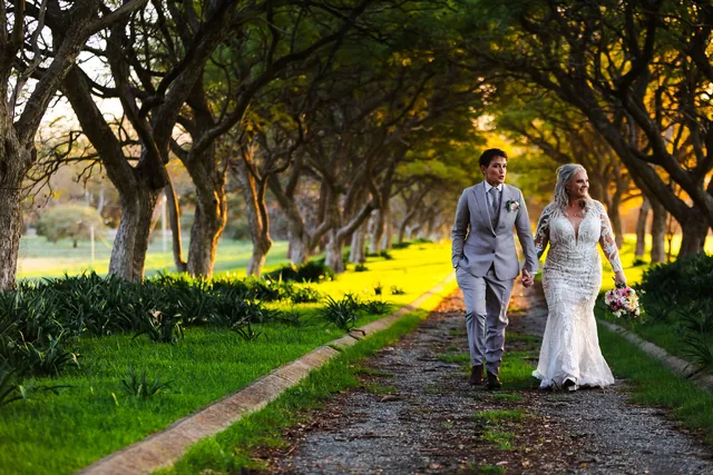 Two brides walking hand in hand down the tree avenue