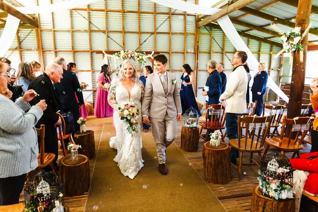 The two brides walking back down the aisle through confetti