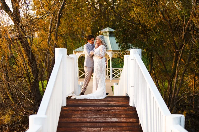 Two brides on the white gazebo steps beneath the autumn trees