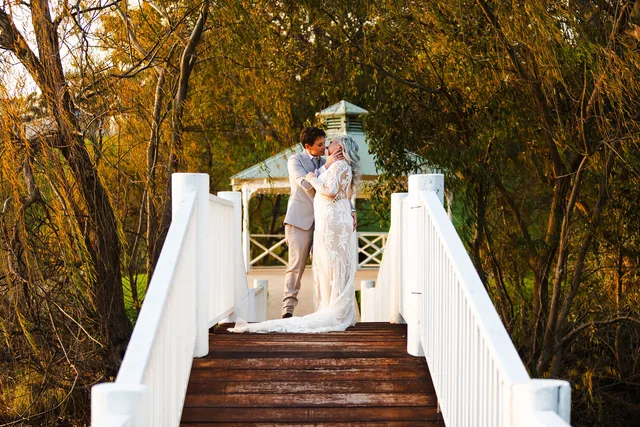 Two brides kissing on the gazebo steps, the dress spilling down behind them