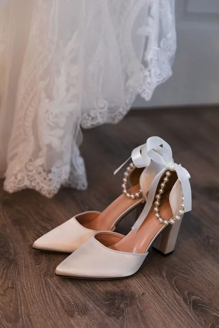 The bride’s pearl-strapped shoes beneath the hem of her lace gown