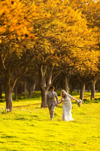 Two brides walking together under a golden canopy of leaves