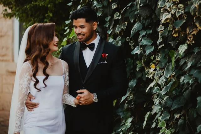 The couple laughing together against the ivy-covered wall