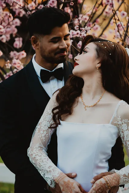 The bride looking up at her groom beneath the spring blossom