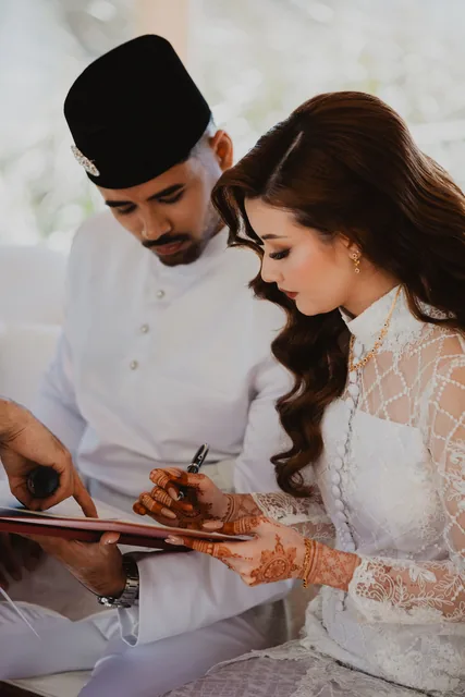 Signing the register, henna dark across the bride’s hands