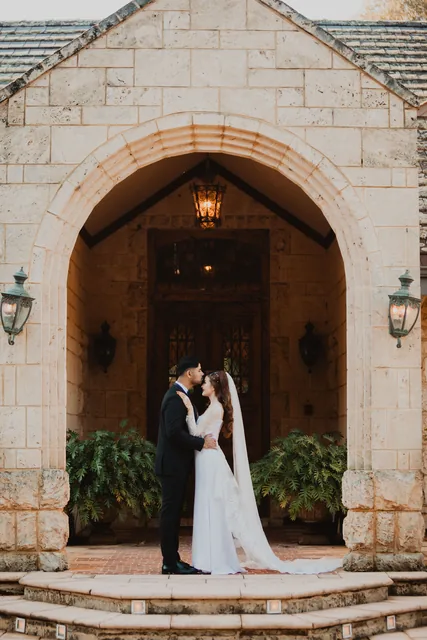 The couple kissing in the Chateau&rsquo;s arched stone doorway at Brookleigh Estate