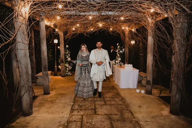 The couple walking the lit arbour at night in traditional dress