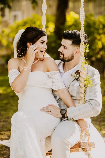 Bride laughing beside her groom on a garden swing