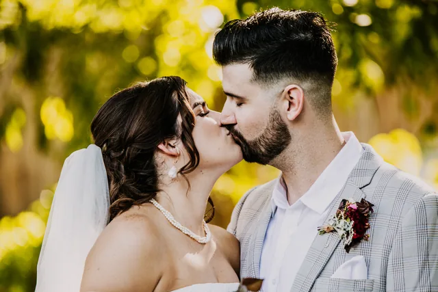 Bride and groom kissing in dappled light
