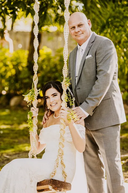 Groom standing beside his bride on the garden swing
