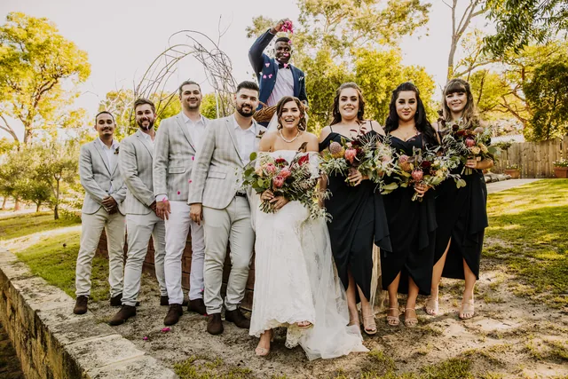 The full bridal party laughing together on the lawn