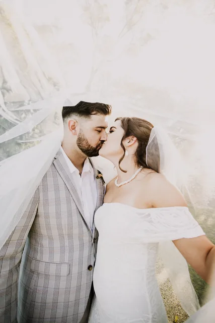 Bride and groom kissing beneath her veil